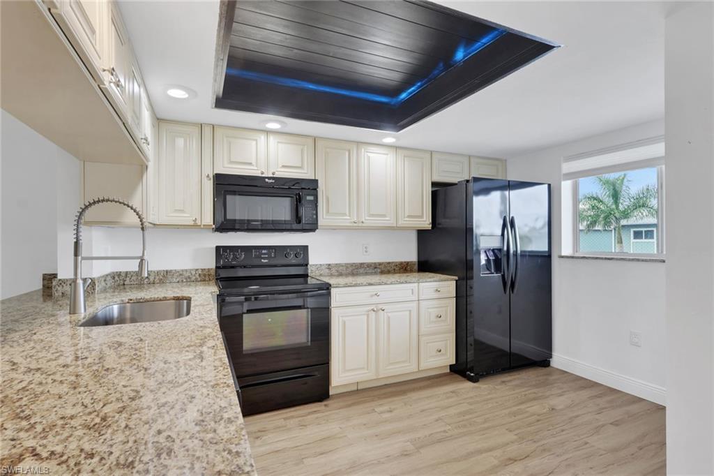 146 Cypress Way East, Unit 7 Naples, FL 34110 - Photo 4 of 27 a kitchen with stainless steel appliances granite countertop a stove refrigerator sink and microwave