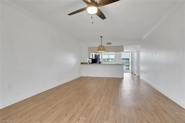 a view of a kitchen with wooden floor a sink a refrigerator and window