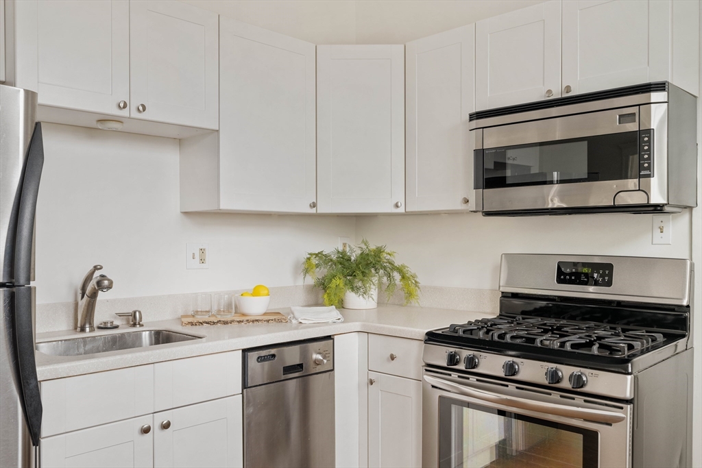 429 Washington Street, Unit 6 Brookline, MA 02446 - Photo 8 of 18 a kitchen with stainless steel appliances granite countertop white cabinets a stove a sink and dishwasher