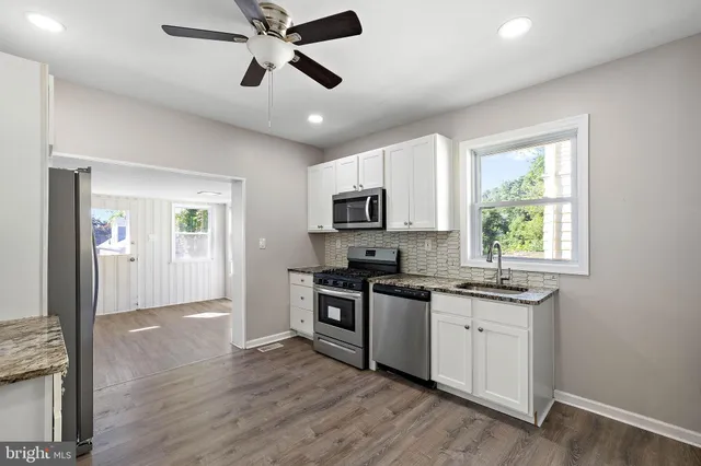 a kitchen with stainless steel appliances granite countertop a stove top oven a sink dishwasher a refrigerator and a microwave