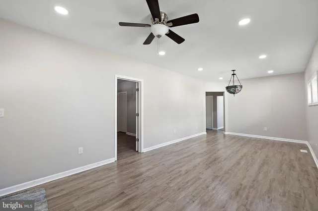 an empty room with wooden floor ceiling fan and windows