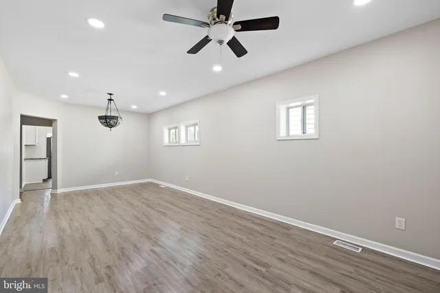 an empty room with wooden floor ceiling fan and windows