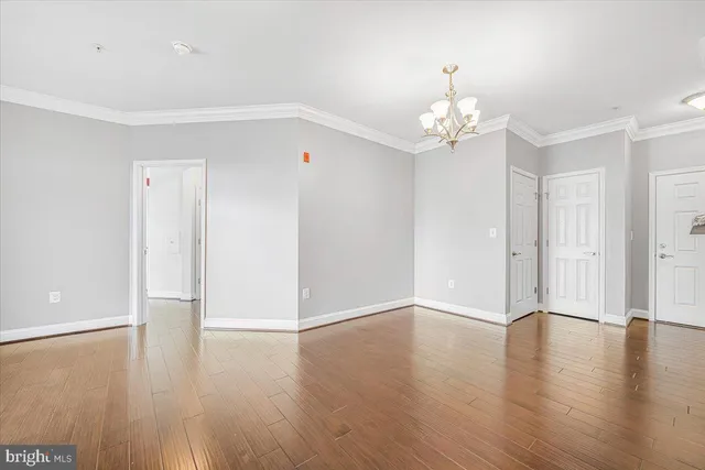 an empty room with wooden floor chandelier fan and windows