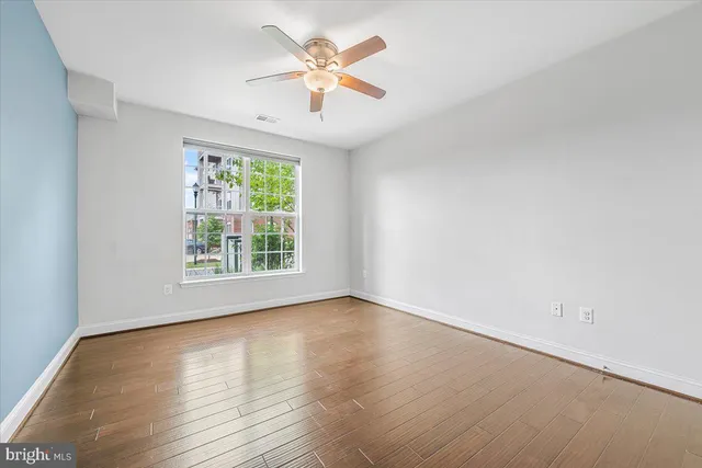a view of an empty room with wooden floor and a window
