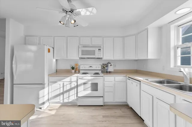 a view of a hallway with wooden floor and a kitchen