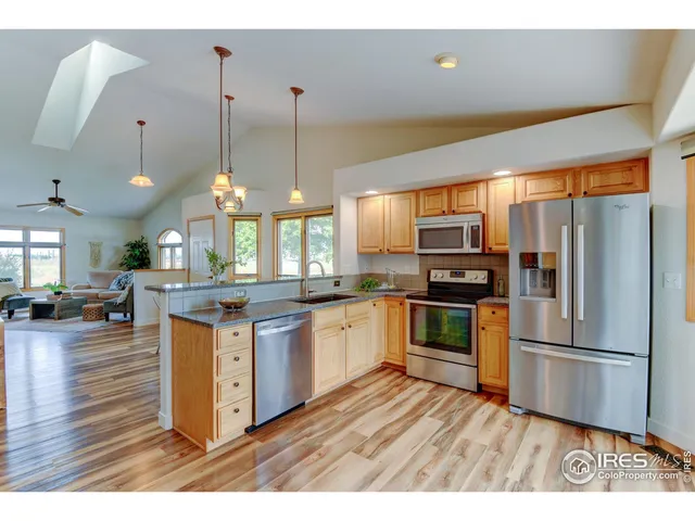 a kitchen with stainless steel appliances granite countertop a refrigerator a sink dishwasher a stove with wooden floor