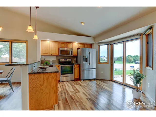 a open kitchen with stainless steel appliances granite countertop a refrigerator a sink a stove and a wooden floors