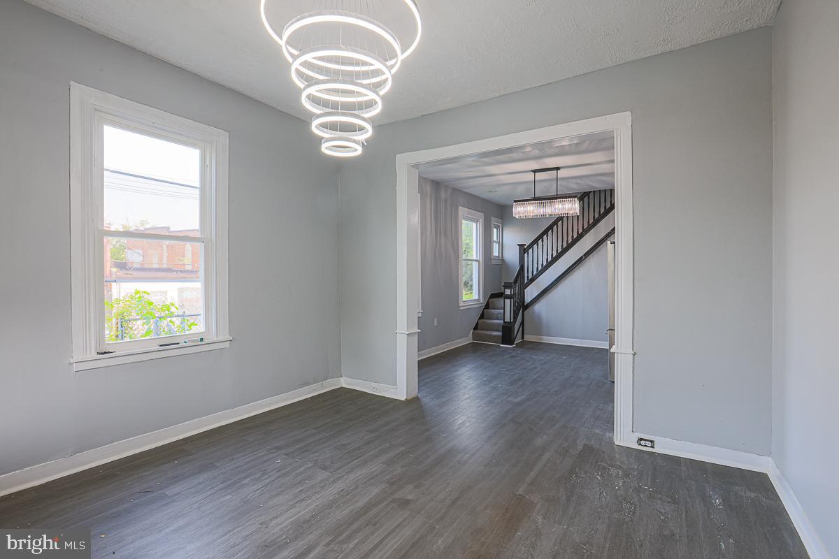 604 East 31st Street Baltimore, MD 21218 - Photo 20 of 50 an empty room with wooden floor chandelier and windows