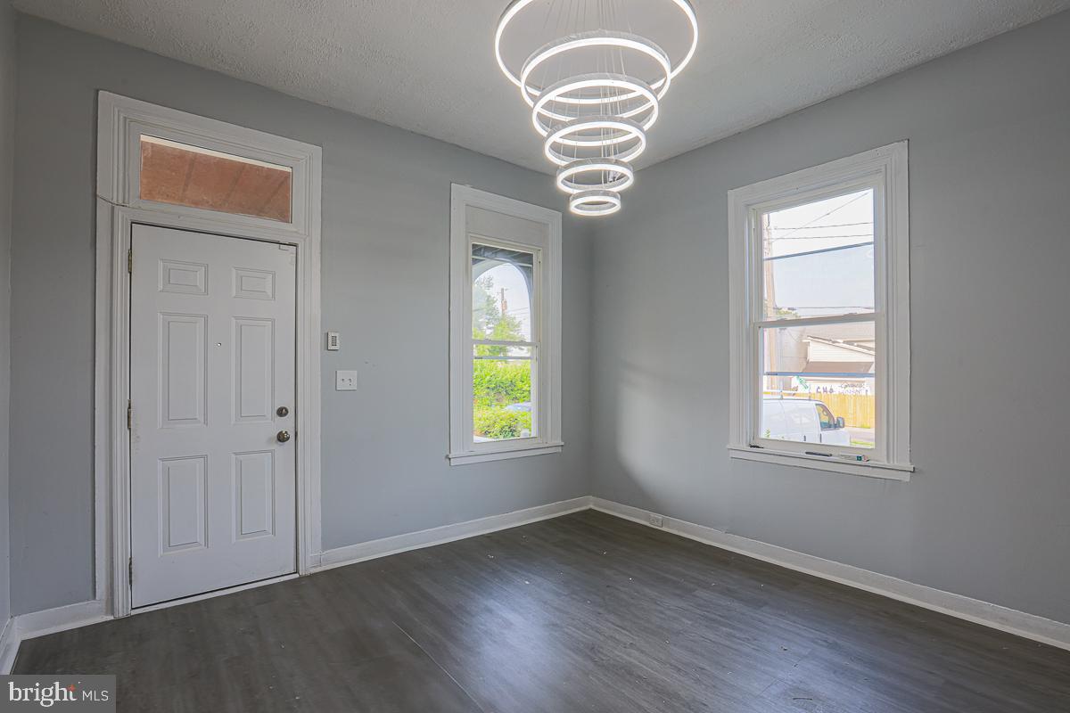604 East 31st Street Baltimore, MD 21218 - Photo 21 of 50 an empty room with wooden floor chandelier and windows