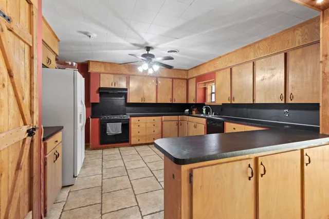 a view of a kitchen with kitchen island a counter top space a sink a refrigerator and a window