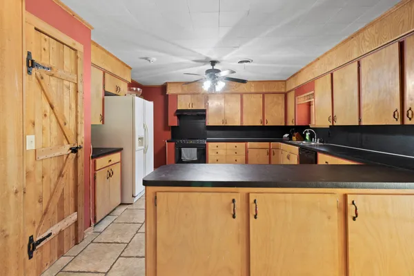 a view of a refrigerator a sink and dishwasher with wooden cabinets