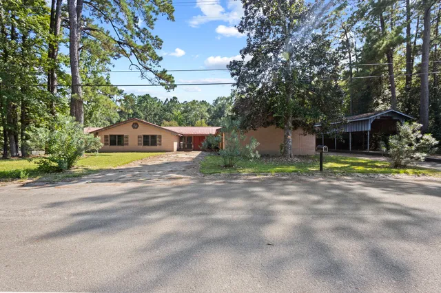 a front view of a house with a garden and trees