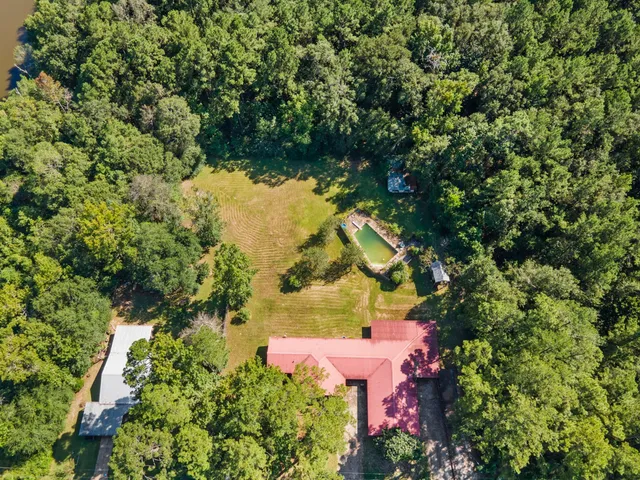 an aerial view of residential house with outdoor space and trees all around