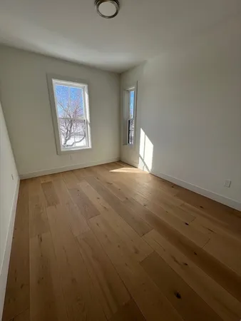 a view of an empty room with wooden floor and window