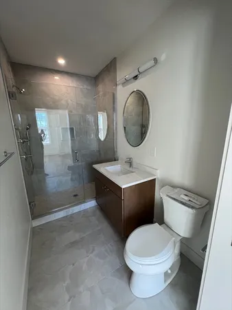 a bathroom with a toilet sink vanity granite and a shower