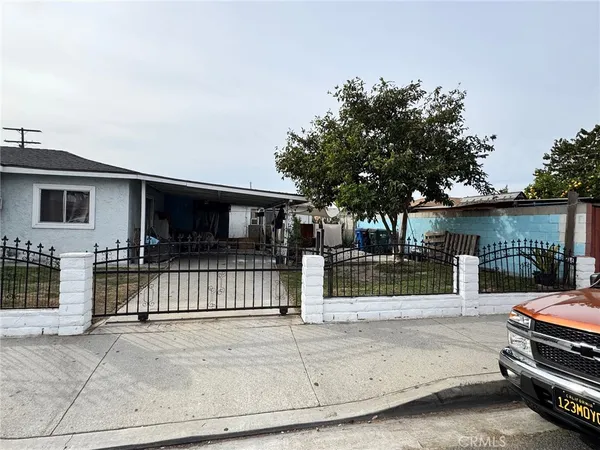 a view of a house with a small yard and large tree