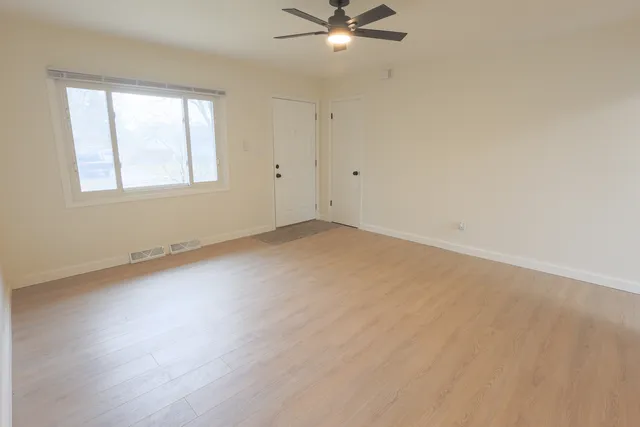 an empty room with a window and a fan