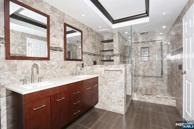 a spacious bathroom with double vanity sinks a large mirror and a bathtub