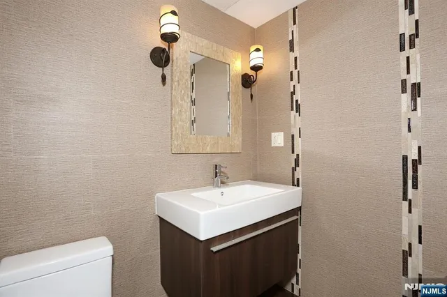 a bathroom with a sink a toilet a mirror and a window