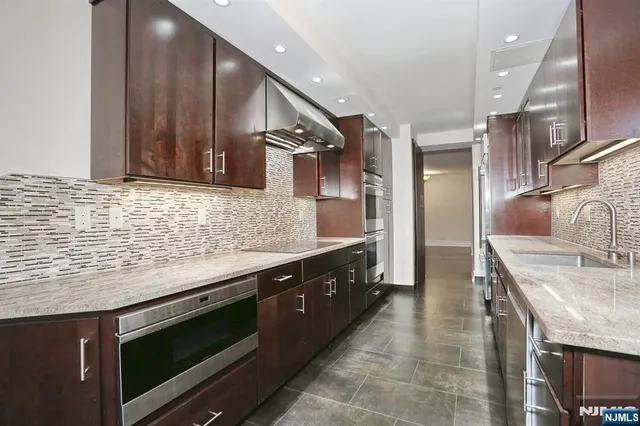 a kitchen with stainless steel appliances kitchen island granite countertop a sink and a stove