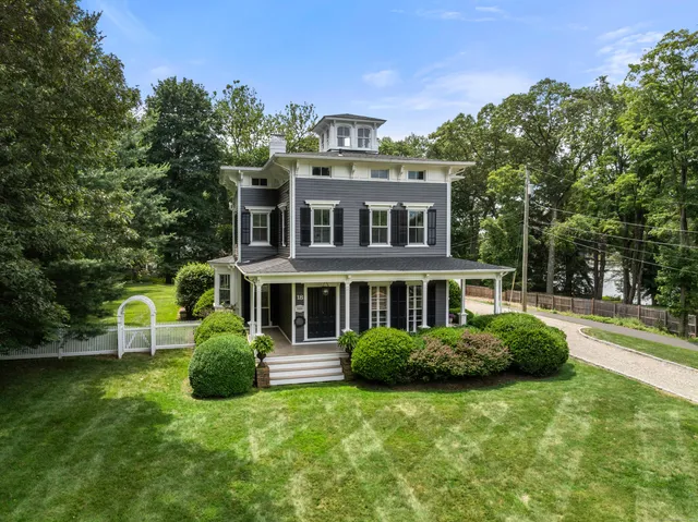 a front view of a house with a garden and trees