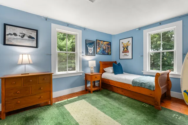 a bedroom with a bed and a dresser next to a window