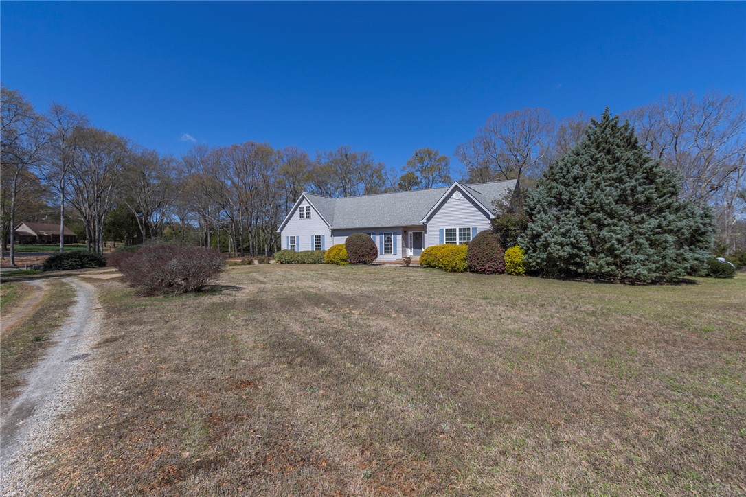 A charming residence awaits, nestled amidst a generous lawn with mature trees and a long driveway.