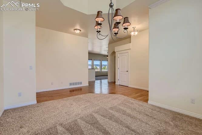 13968 Windy Oaks Road Colorado Springs, CO 80921 - Photo 11 of 34 a view of a room with a chandelier and wooden floor