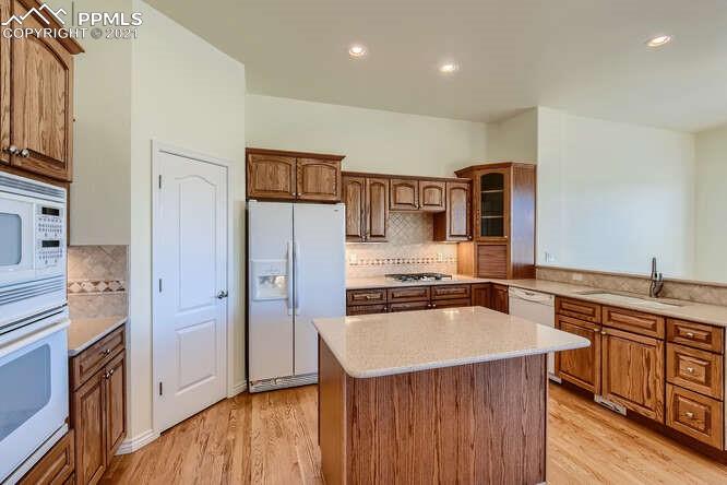 13968 Windy Oaks Road Colorado Springs, CO 80921 - Photo 12 of 34 a kitchen with a refrigerator a sink and wooden cabinets