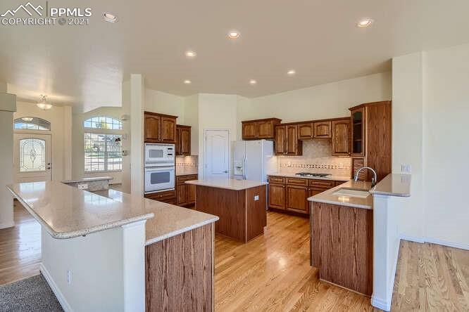 13968 Windy Oaks Road Colorado Springs, CO 80921 - Photo 13 of 34 a large kitchen with stainless steel appliances granite countertop a lot of counter space and wooden floors