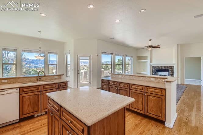 13968 Windy Oaks Road Colorado Springs, CO 80921 - Photo 14 of 34 a kitchen with stainless steel appliances granite countertop a stove a sink dishwasher a kitchen island with wooden cabinets and floor