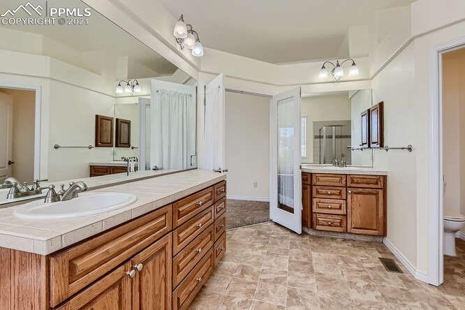 13968 Windy Oaks Road Colorado Springs, CO 80921 - Photo 18 of 34 a spacious bathroom with a sink double vanity and a mirror