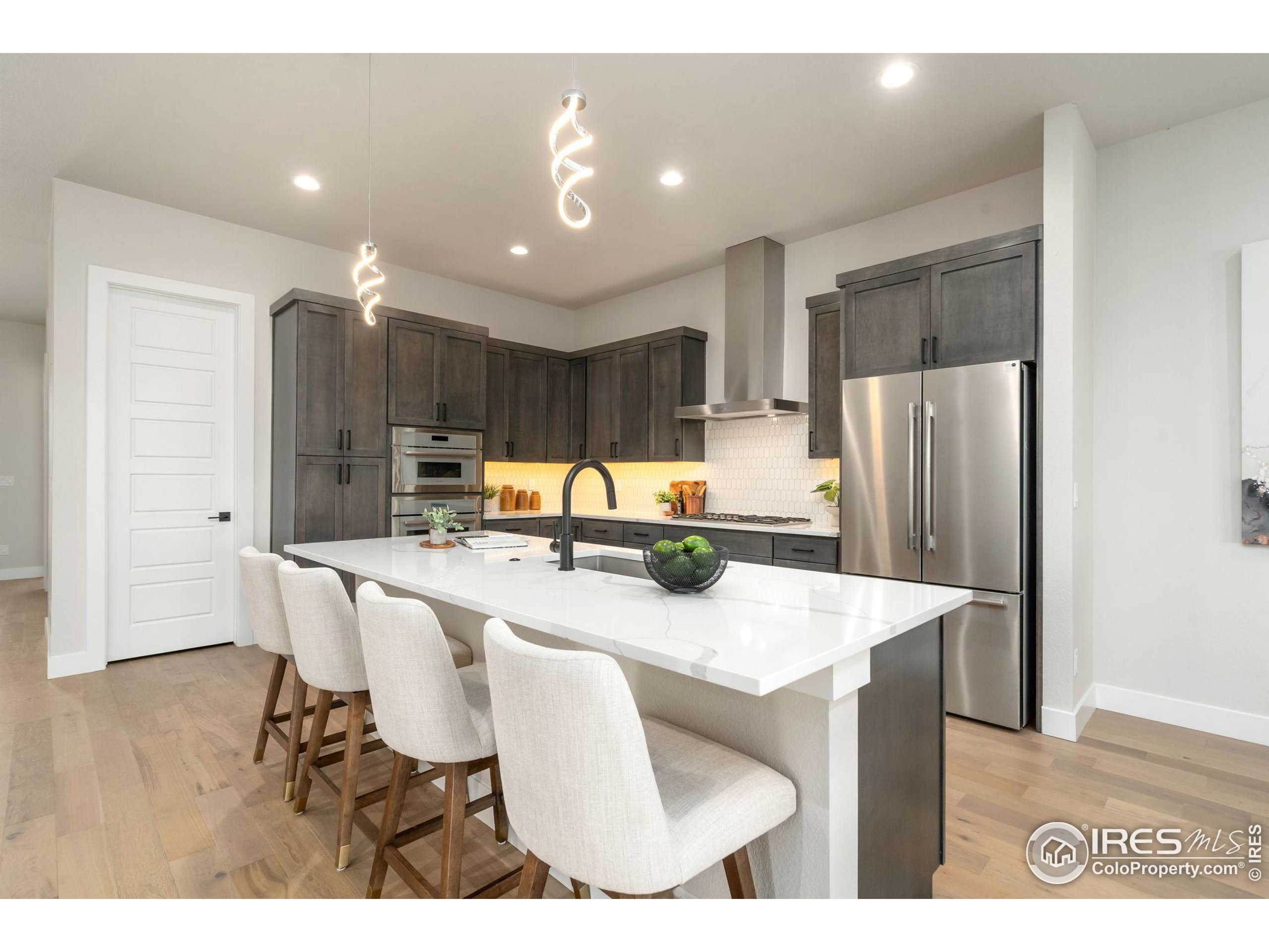 1729 Beachside Drive Windsor, CO 80550 - Photo 10 of 49 a kitchen with stainless steel appliances granite countertop a refrigerator a sink a stove a dining table and chairs