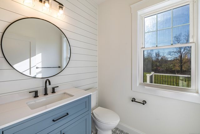 a bathroom with a sink a mirror a toilet and a window