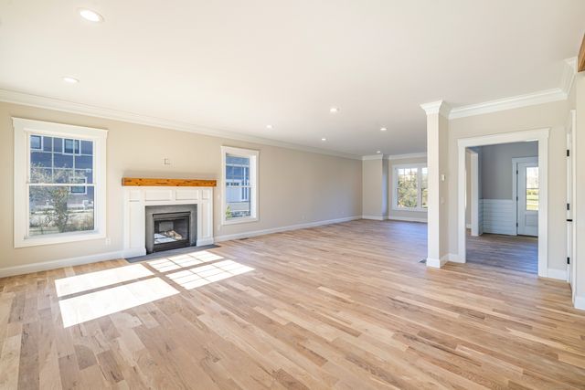 a view of an empty room with wooden floor fireplace and a window