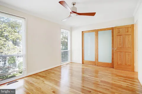 a view of empty room with wooden floor and fan