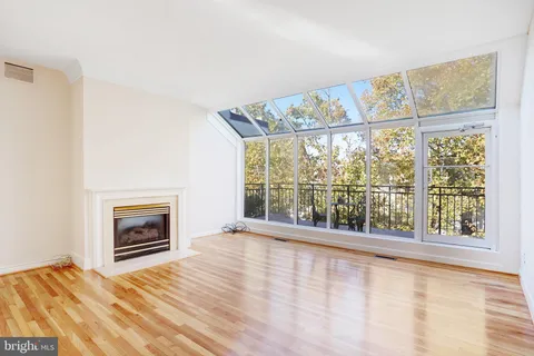 a view of an empty room with a window and kitchen view