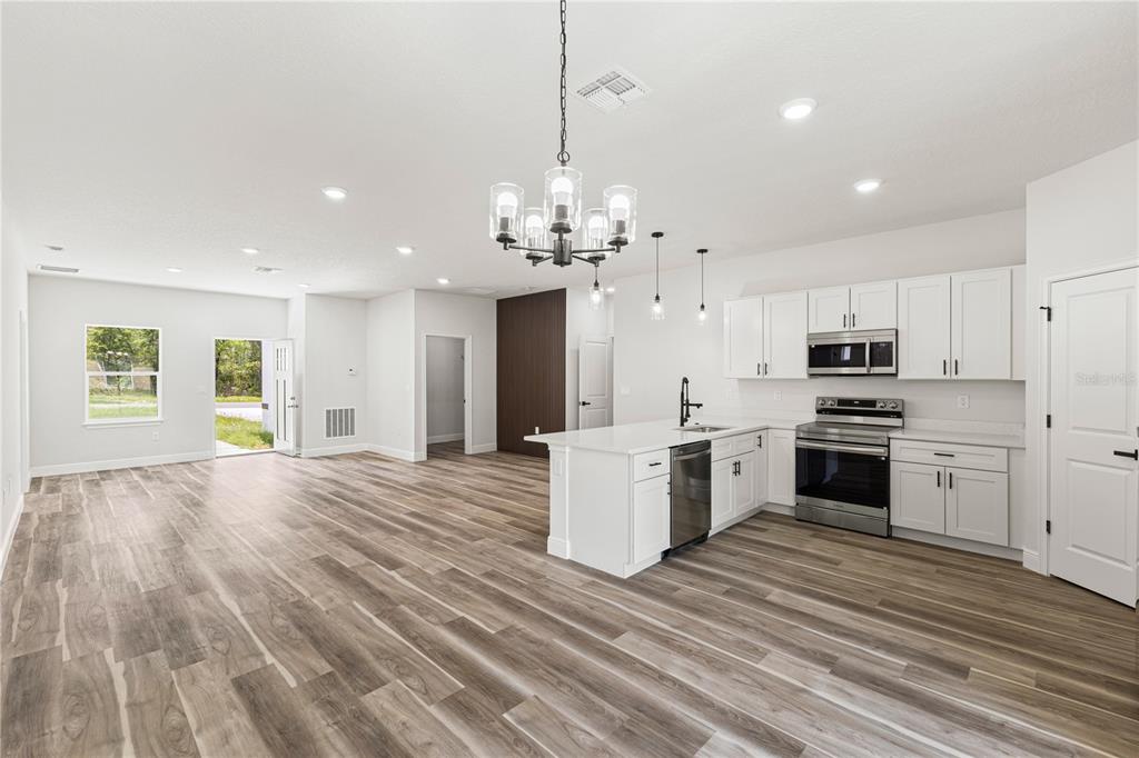 5217 Southwest 165th St Road Ocala, FL 34473 - Photo 10 of 35 a kitchen with stove a refrigerator and a fireplace with wooden floor