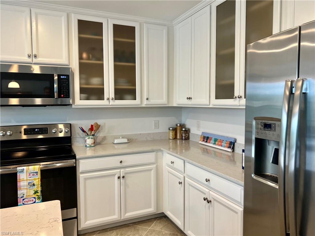 9584 Trevi Court, Unit 5223 Naples, FL 34113 - Photo 11 of 42 a kitchen with stainless steel appliances white cabinets and a refrigerator