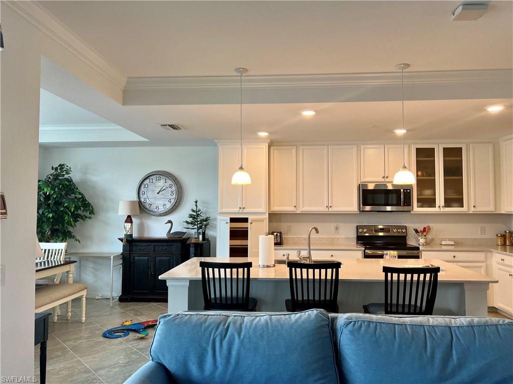 9584 Trevi Court, Unit 5223 Naples, FL 34113 - Photo 24 of 42 a kitchen with a refrigerator a stove a sink and a dining table with wooden floor