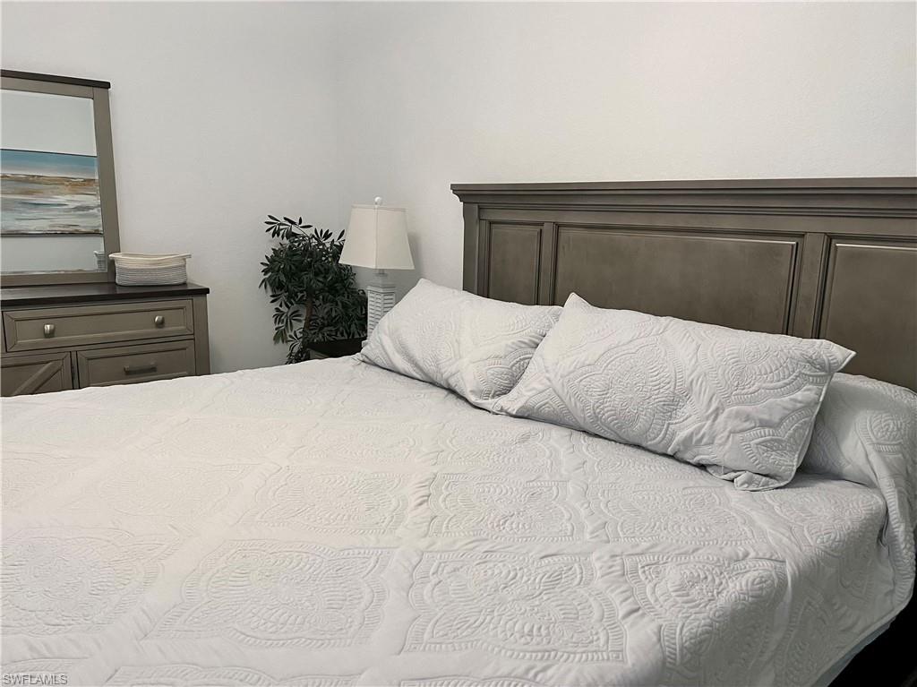 9584 Trevi Court, Unit 5223 Naples, FL 34113 - Photo 26 of 42 a bedroom with a large bed and a potted plant