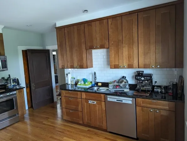 a kitchen with stainless steel appliances granite countertop a refrigerator a stove a sink and dishwasher with wooden cabinets
