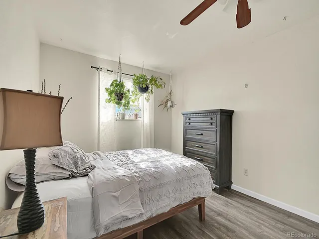 a bedroom with a bed a lamp and wooden floor