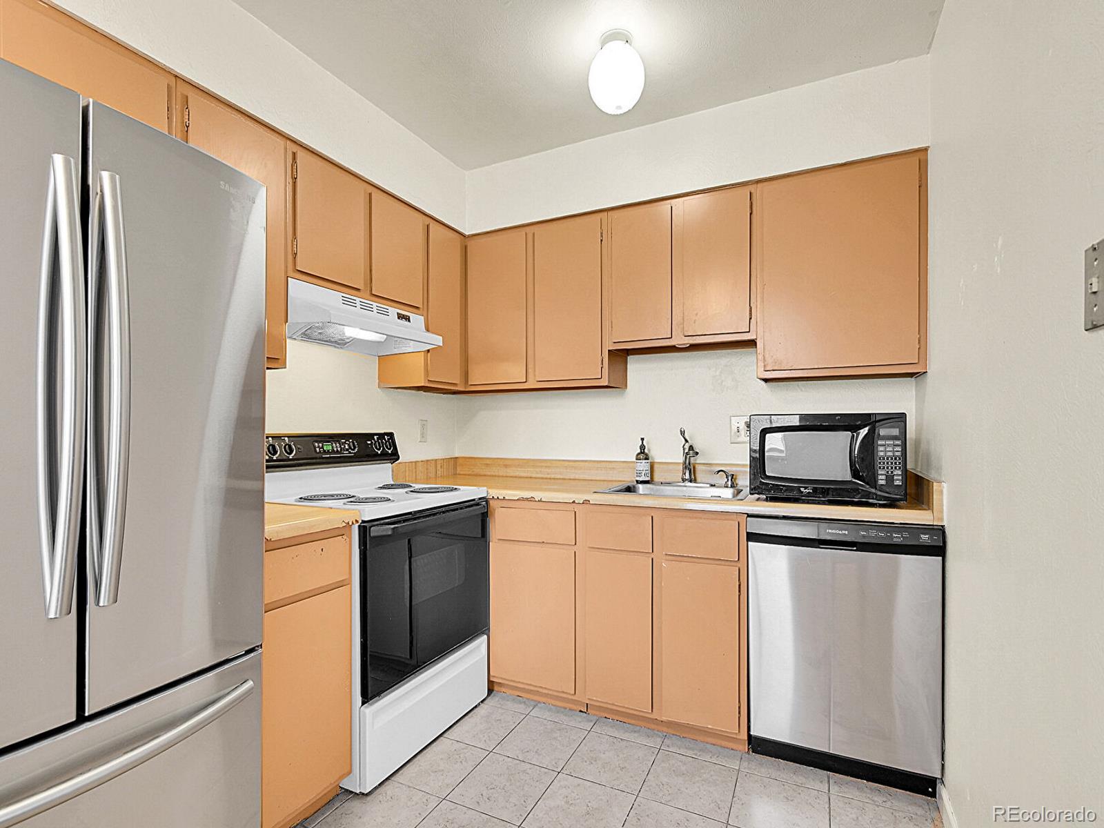 9340 West 49th Avenue, Unit 218 Wheat Ridge, CO 80033 - Photo 7 of 31 a kitchen with white cabinets stainless steel appliances and a sink