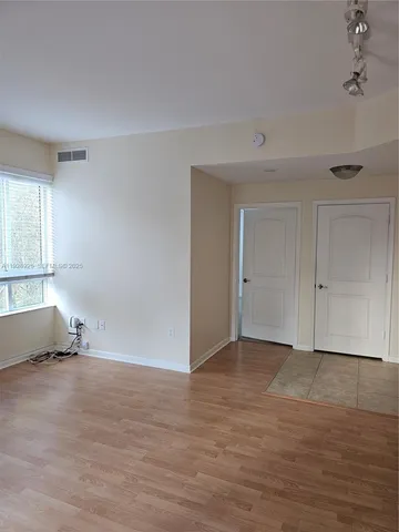 a view of empty room with wooden floor and fan