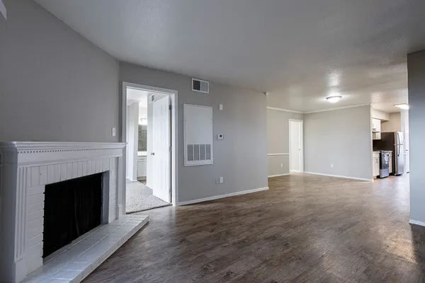 a view of an empty room with wooden floor and a fireplace