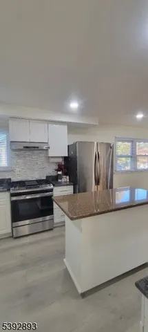 a kitchen with stainless steel appliances granite countertop a refrigerator a stove and a sink