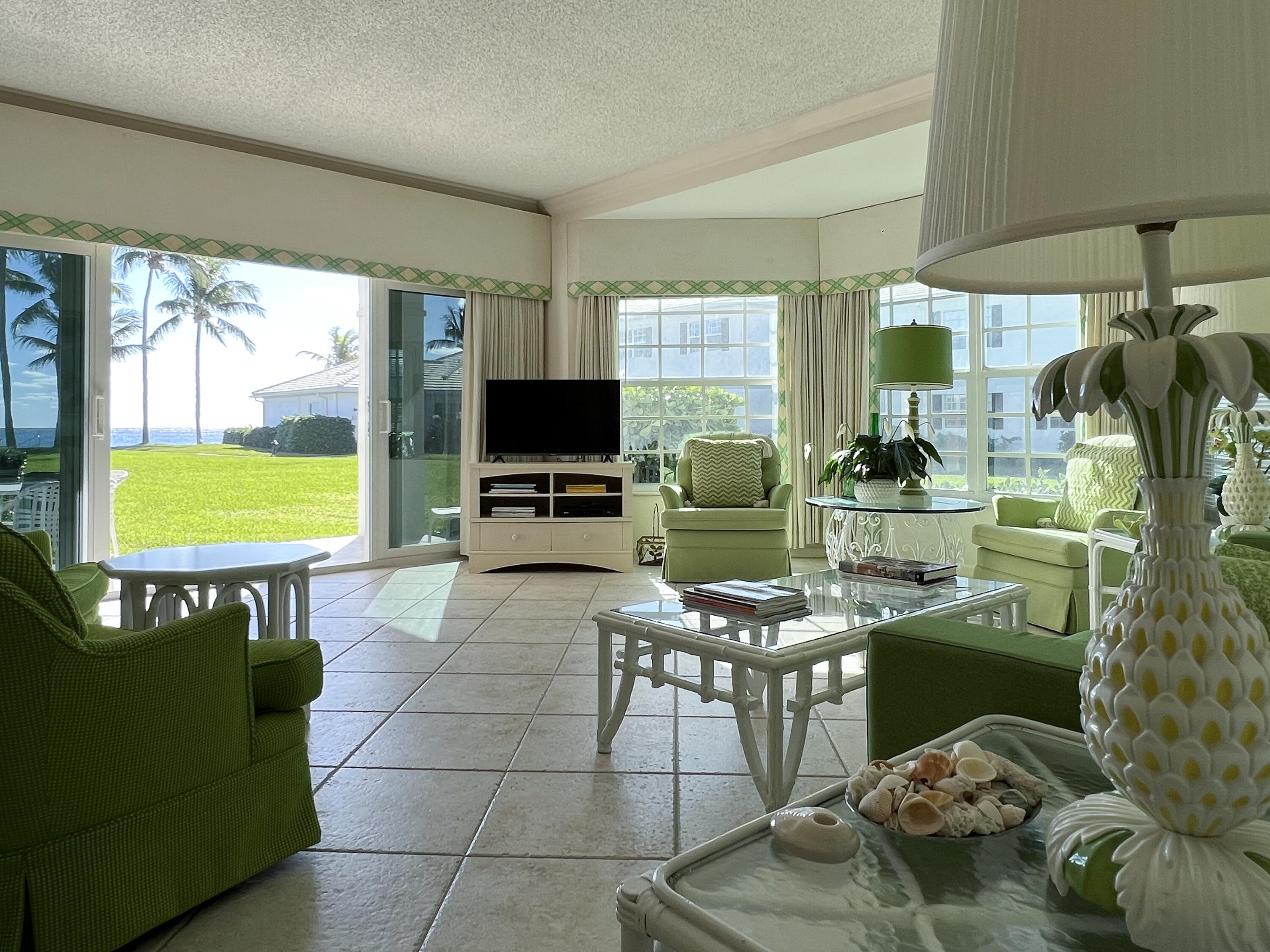 400 South Ocean Boulevard, Unit 103A Lake Worth, FL 33462 - Photo 2 of 12 a living room with furniture a flat screen tv and a floor to ceiling window