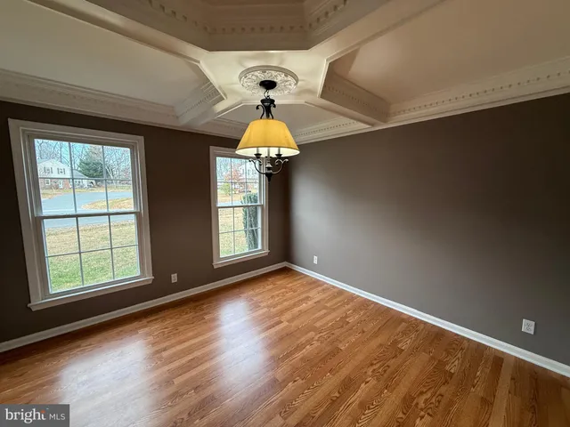 an empty room with wooden floor windows and chandelier