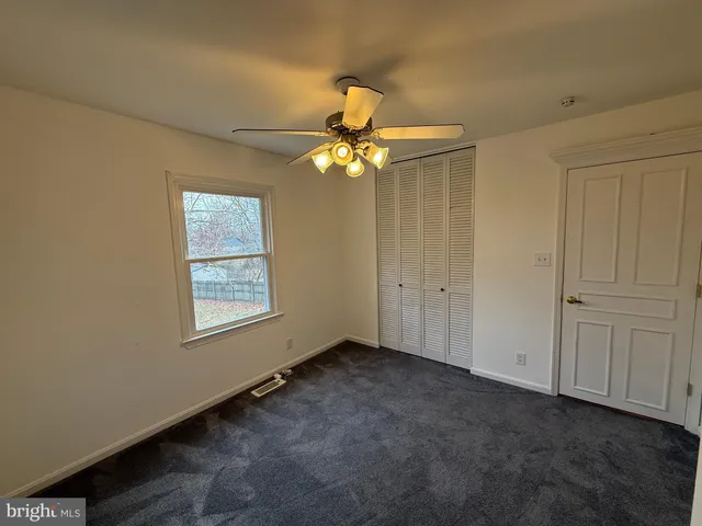 an empty room with windows and fan
